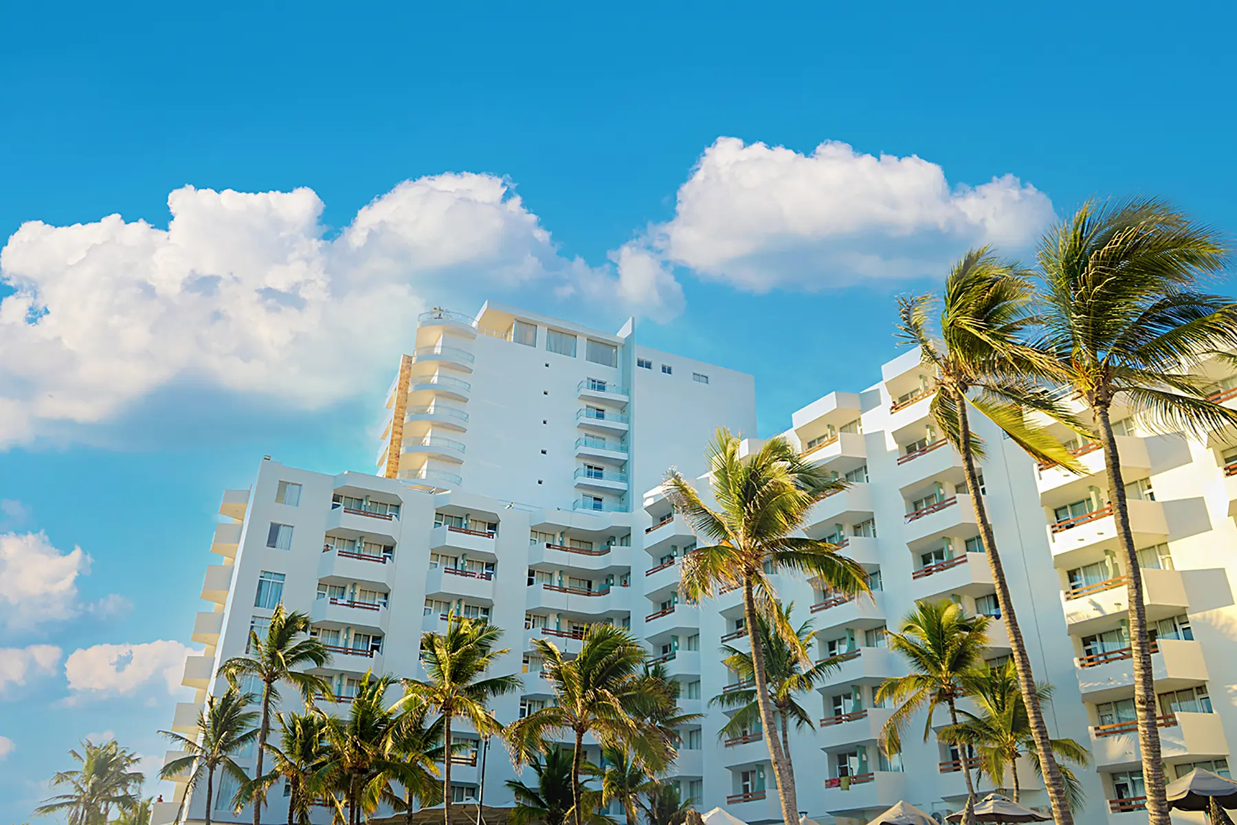 Fachada de hotel Oceano Palace con habitaciones vista al mar y palmeras en Mazatlán